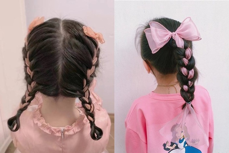 Bé gái với tóc tết và kẹp nơ màu hồng dễ thương