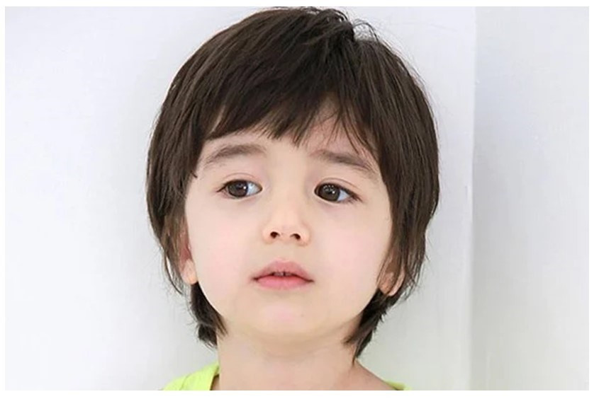 Bé trai với mái tóc thẳng dài có mái, tạo điểm nhấn cho mái tóc dày