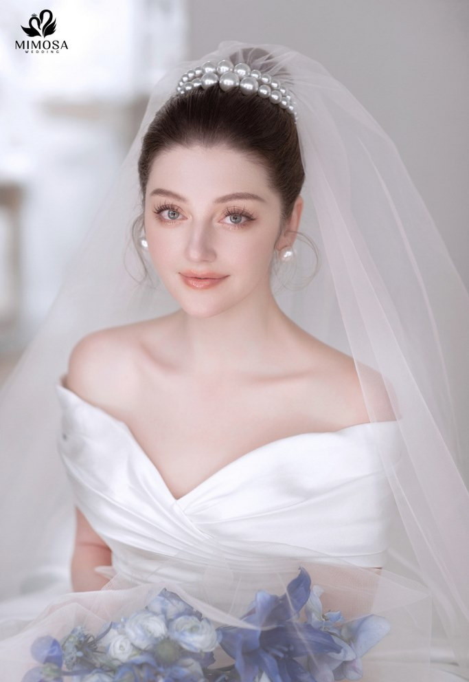 Cô dâu quyến rũ với tóc dài buộc nửa đầu và vương miện tinh xảo, phong cách phù hợp cho cô dâu tóc ngắn ngang vai.