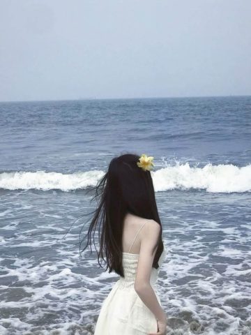 Cô gái tóc ngắn duyên dáng chụp ảnh đi biển từ phía sau, ngắm nhìn hoàng hôn trên biển