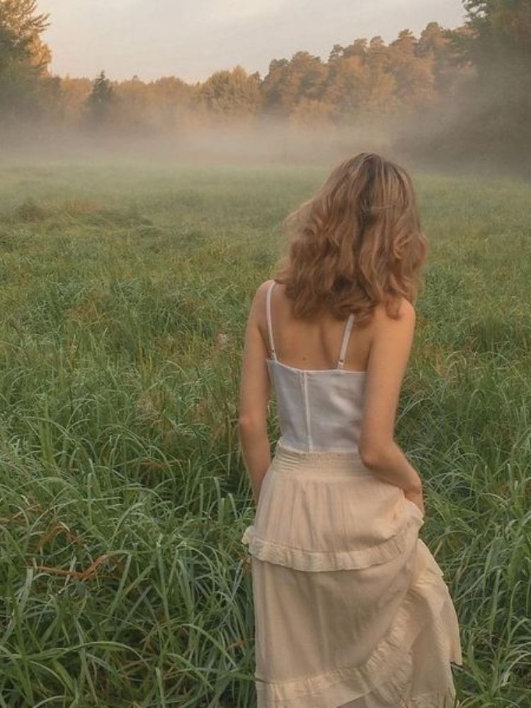 Cô gái tóc ngắn ngồi tựa lưng vào cửa sổ, mái tóc bồng bềnh che đi một phần gương mặt, tạo nên một hình ảnh đầy suy tư và u buồn