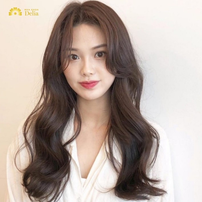 Cô gái với kiểu tóc dài uốn xoăn nhẹ, tôn lên vẻ đẹp tự nhiên cho khuôn mặt dài, một trong các kiểu tóc nữ năm 2024