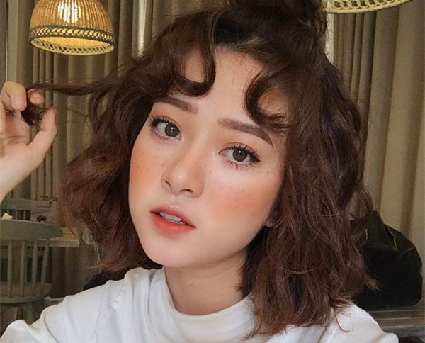 Cô gái với kiểu tóc ngắn uốn xoăn phồng nhuộm nâu, phong cách quyến rũ