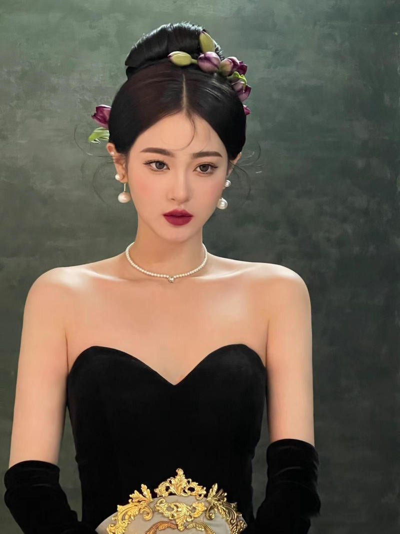 Cô gái với tóc búi cao gọn gàng, cài hoa trắng tinh tế làm điểm nhấn