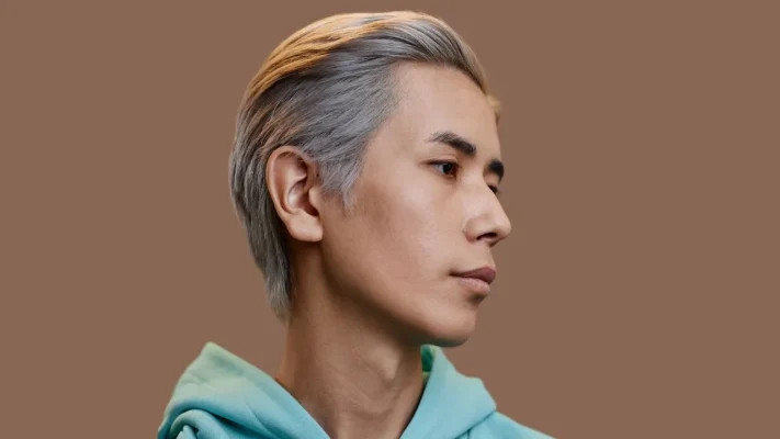 Kiểu tóc ngắn chải lược được vuốt gel bóng bẩy, mái tóc đen nhánh của người đàn ông lớn tuổi