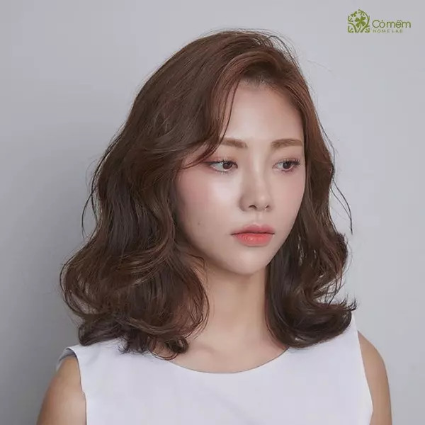 Mái tóc ngắn ngang vai uốn gợn sóng nhẹ, giúp làm mềm mại đường nét khuôn mặt vuông