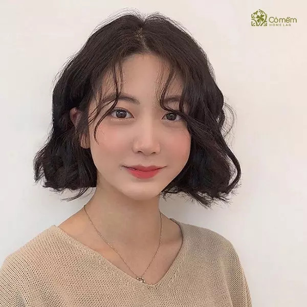 Mái tóc ngắn uốn sóng lớn bồng bềnh, giúp làm dịu đường nét khuôn mặt vuông góc cạnh