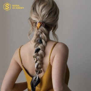 Mái tóc thắt bím dịu dàng kết hợp khăn lụa, tạo điểm nhấn độc đáo và nữ tính.