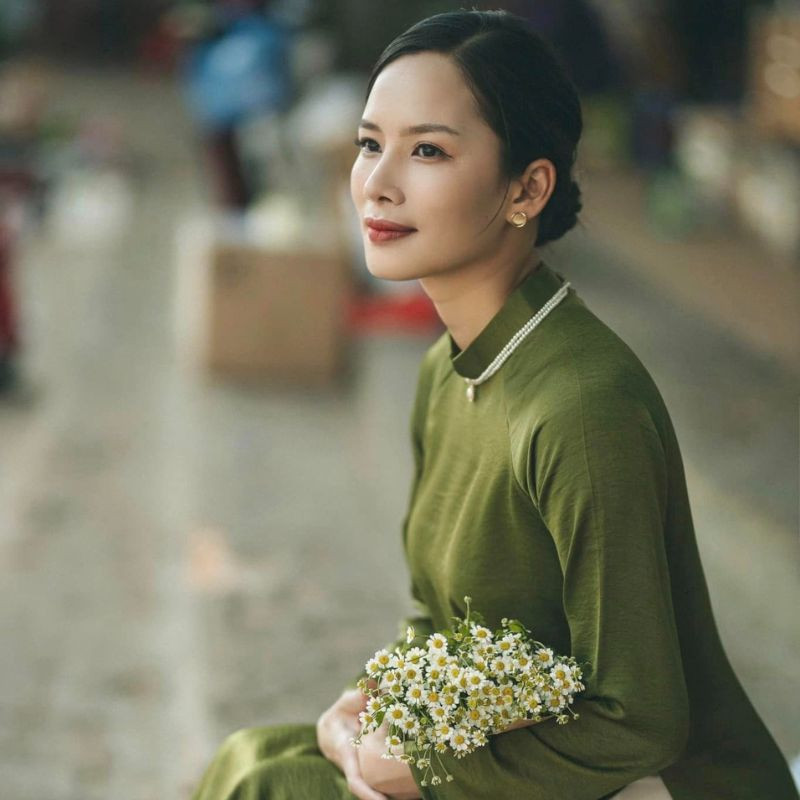 Mẫu tóc búi thấp kết hợp ngôi 7/3 vuốt gọn, cùng tóc mai uốn nhẹ, tạo phong thái trang nhã khi mặc áo dài