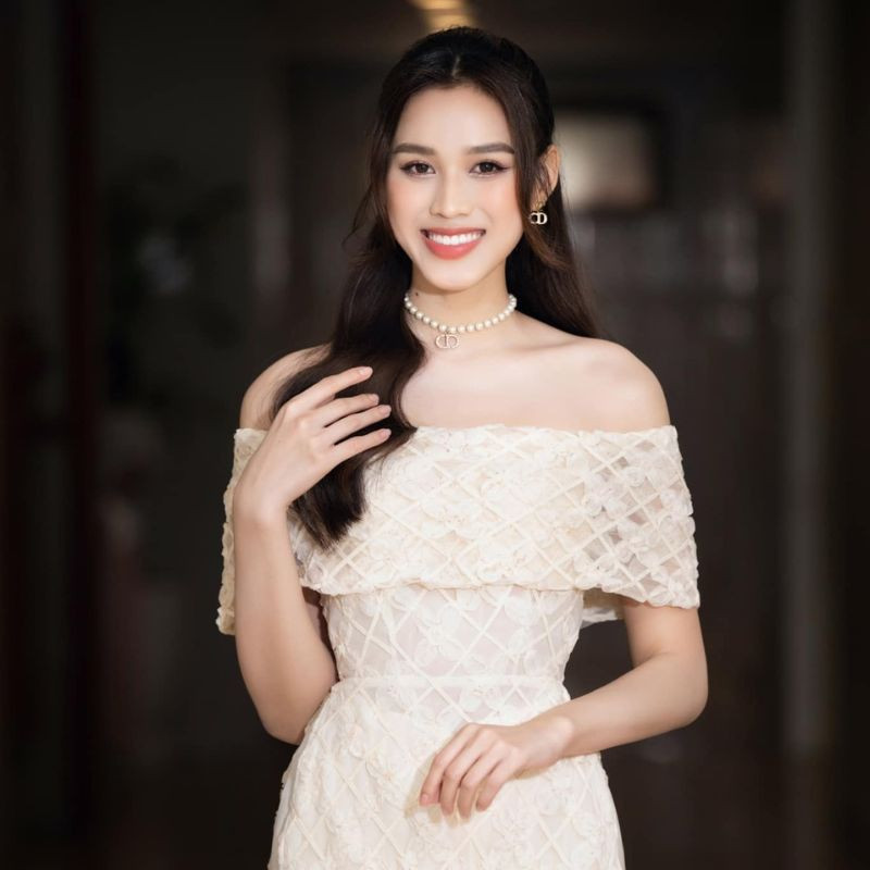 Mẫu tóc uốn gợn sóng, cột nửa đầu cùng mái bay lơi che khuyết điểm, phù hợp với áo dài trễ vai