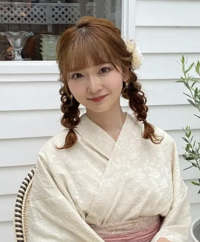 Một cô gái trẻ với kiểu tóc bện đôi được nới lỏng nhẹ nhàng, kết hợp với kimono ren trắng, toát lên vẻ đẹp nữ tính và trẻ trung, là một trong số kiểu tóc đặc trưng của Lyve.