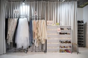 Một phụ nữ mặc kimono nổi bật trong cửa hàng cho thuê, xung quanh là nhiều bộ kimono và phụ kiện, gợi ý một nơi lý tưởng để lựa chọn một số kiểu tóc phù hợp với trang phục truyền thống tại Lyve Hana no Wafuku.