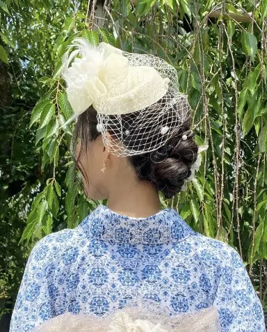 Một phụ nữ với kiểu tóc búi thấp thanh lịch, trang trí bằng trâm cài tóc tinh xảo, đang tạo dáng với kimono màu xanh tím than, thể hiện vẻ đẹp sang trọng và truyền thống, một trong số kiểu tóc yêu thích tại Lyve.