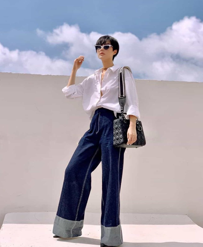 Người phụ nữ tóc ngắn thanh lịch với áo sơ mi trắng và quần jeans ống rộng