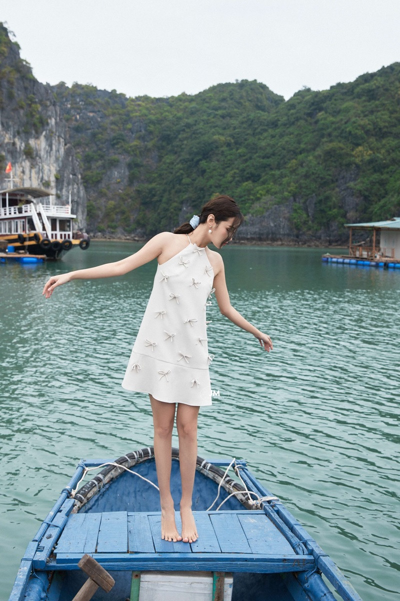 Người phụ nữ với kiểu tóc búi gọn gàng và đầm yếm đính nơ dự tiệc