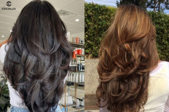 Người phụ nữ với mái tóc dài uốn lọn to sóng nước màu nâu, đang cười nhẹ nhàng, thể hiện vẻ đẹp thanh lịch và nữ tính