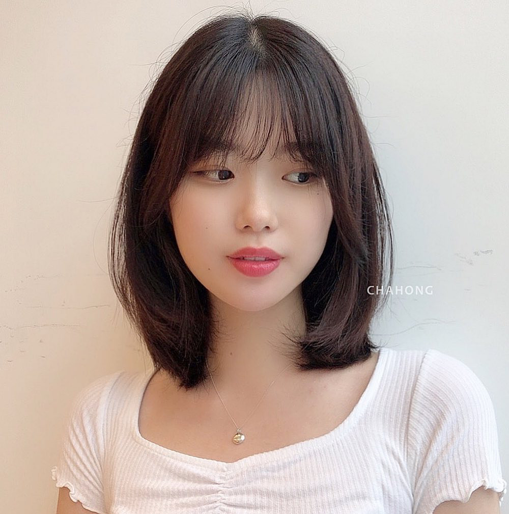 Phụ nữ trung niên với mái tóc ngắn uốn nhẹ và mái thưa tự nhiên