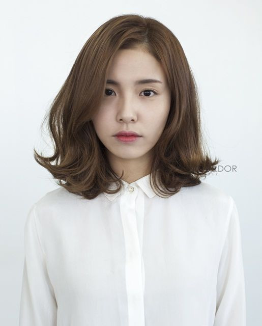 Phụ nữ trung niên với tóc ngang vai xoăn sóng nước, tạo vẻ đẹp dịu dàng