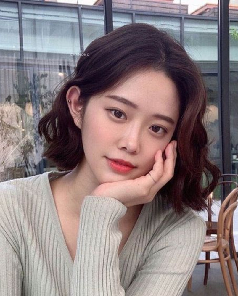 Thể hiện đường nét khuôn mặt với tóc ngắn layer xoăn nhẹ không mái.