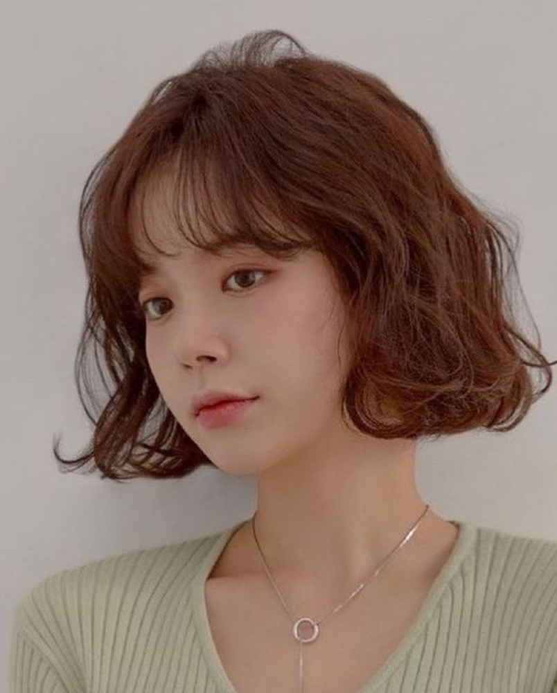 Tóc ngắn layer xoăn nhẹ kết hợp mái thưa giúp che khuyết điểm trán cao.