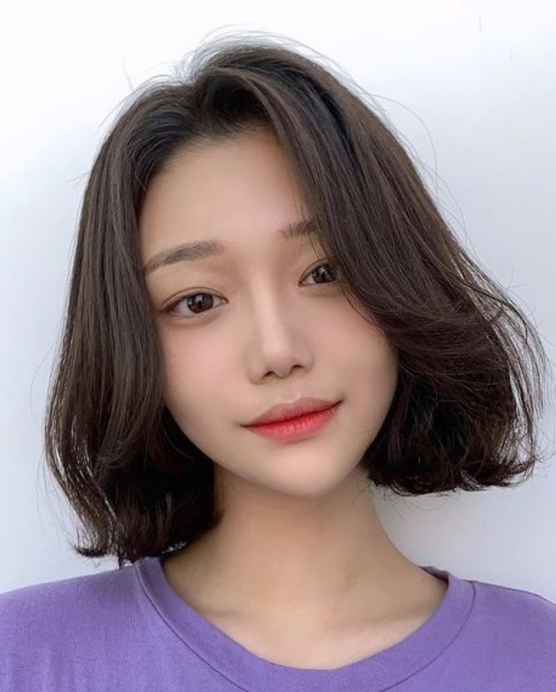 Tóc ngắn layer xoăn nhẹ với mái dài hai bên tạo vẻ gọn gàng và tươi tắn.