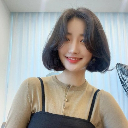 Tóc ngắn rẽ ngôi giữa tạo vẻ thanh thoát cho gương mặt tròn vuông.