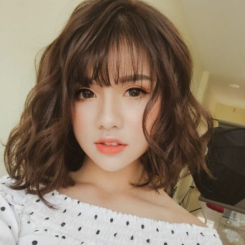 Tóc ngang vai uốn gợn sóng bồng bềnh giúp khuôn mặt vuông tròn trông trẻ trung và năng động hơn.