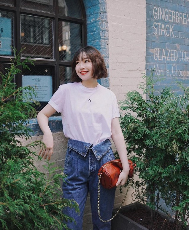 Cô gái tóc ngắn diện áo thun đen và quần jean rách gối, thể hiện sự năng động