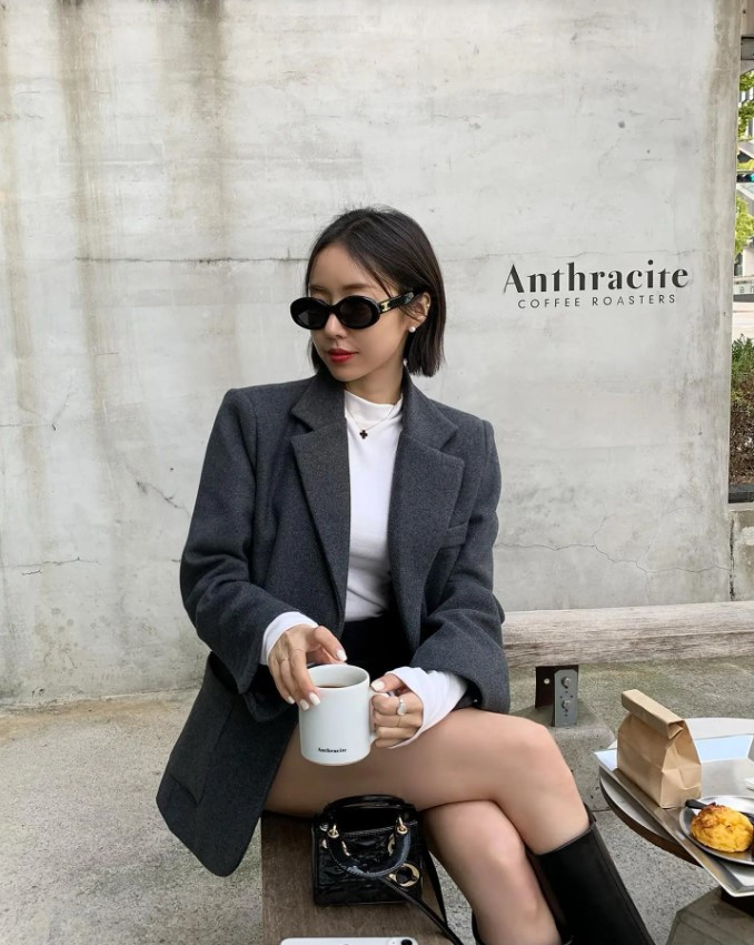 Cô gái tóc ngắn diện blazer đen và quần short, kết hợp boot cao cổ cá tính