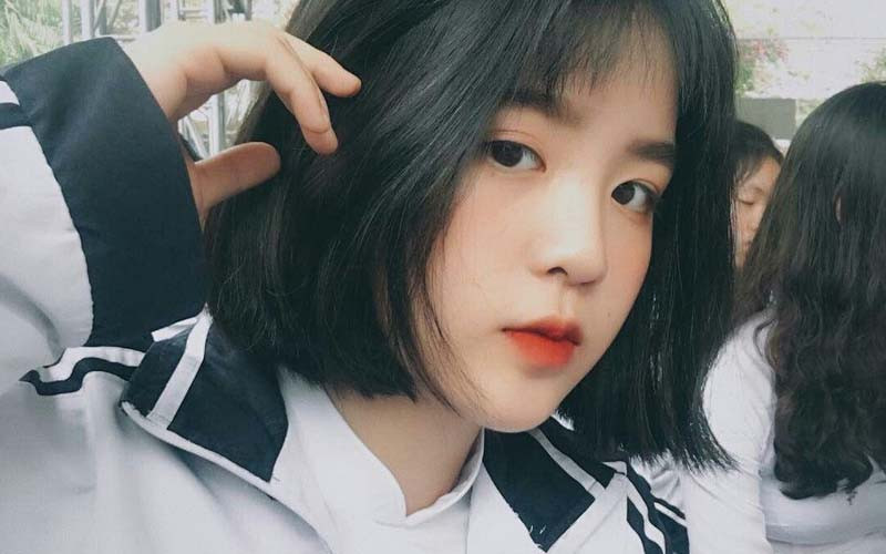 Cô gái tóc ngắn ngước nhìn với vẻ mặt suy tư, thể hiện sự băn khoăn về quyết định cắt tóc