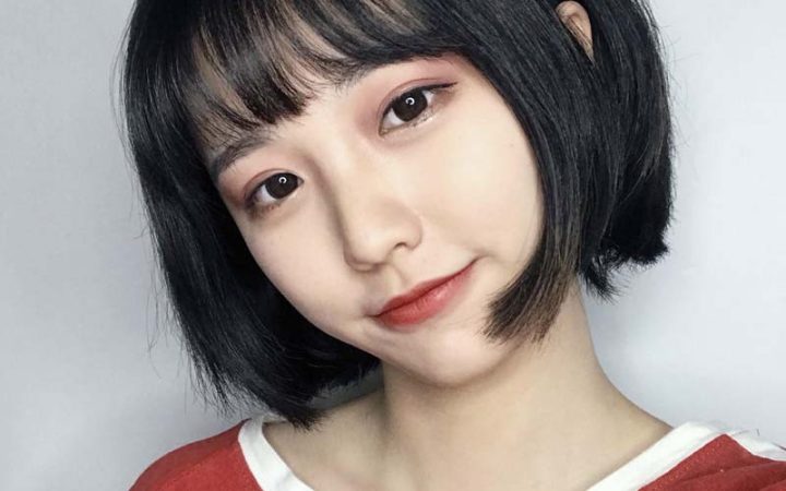 Hình ảnh cô gái cười tươi với mái tóc tém năng động, thể hiện niềm vui sau khi thay đổi kiểu tóc