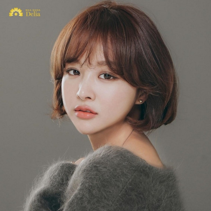 Mẫu tóc bob ngang vai uốn cụp kết hợp mái thưa, giúp mặt dài trông đầy đặn hơn, là xu hướng tóc nữ 2024.