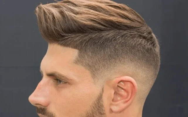 Mohawk hiện đại với phần tóc giữa dài hơn, tạo kiểu sóng nhẹ và hai bên được cạo fade cao, mang lại vẻ ngoài ấn tượng