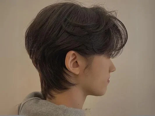 Một người đàn ông với kiểu tóc Mullet được tạo kiểu gọn gàng hơn, phần tóc sau gáy dài vừa phải, mang vẻ lãng tử