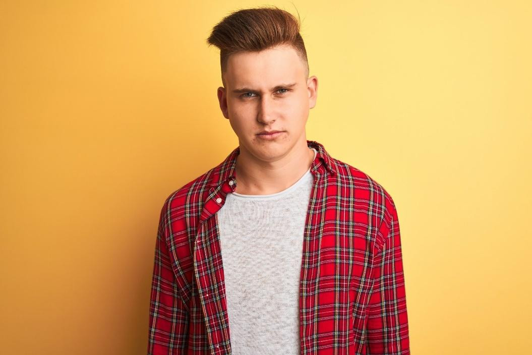 Tóc highlight cho nam: người đàn ông da trắng mặc áo sơ mi kẻ sọc đỏ với những sợi highlight màu đồng trên mái tóc nâu