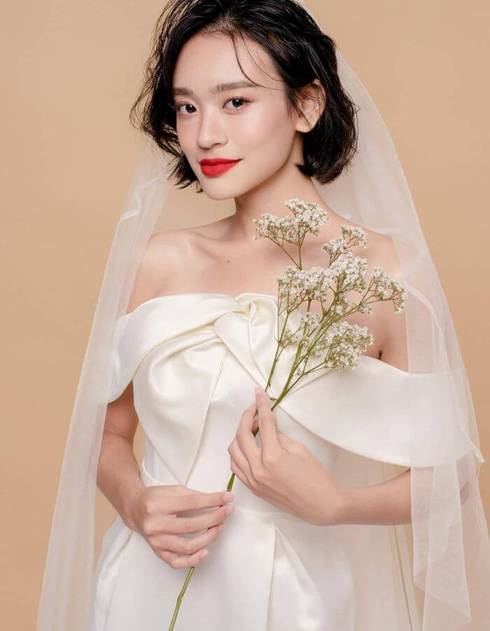 Tóc ngắn đội mấn thanh lịch, phù hợp với áo dài cưới truyền thống, tôn lên vẻ đẹp trang nhã của cô dâu.