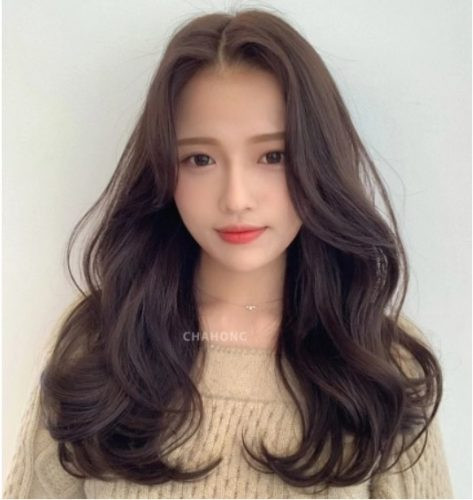 Tóc uốn xoăn mái phồng hai bên tạo độ cân đối cho gò má cao