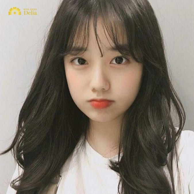 Tóc xoăn lơi với mái ngang, tạo cảm giác gương mặt ngắn hơn, là lựa chọn lý tưởng cho kiểu tóc nữ năm 2024.